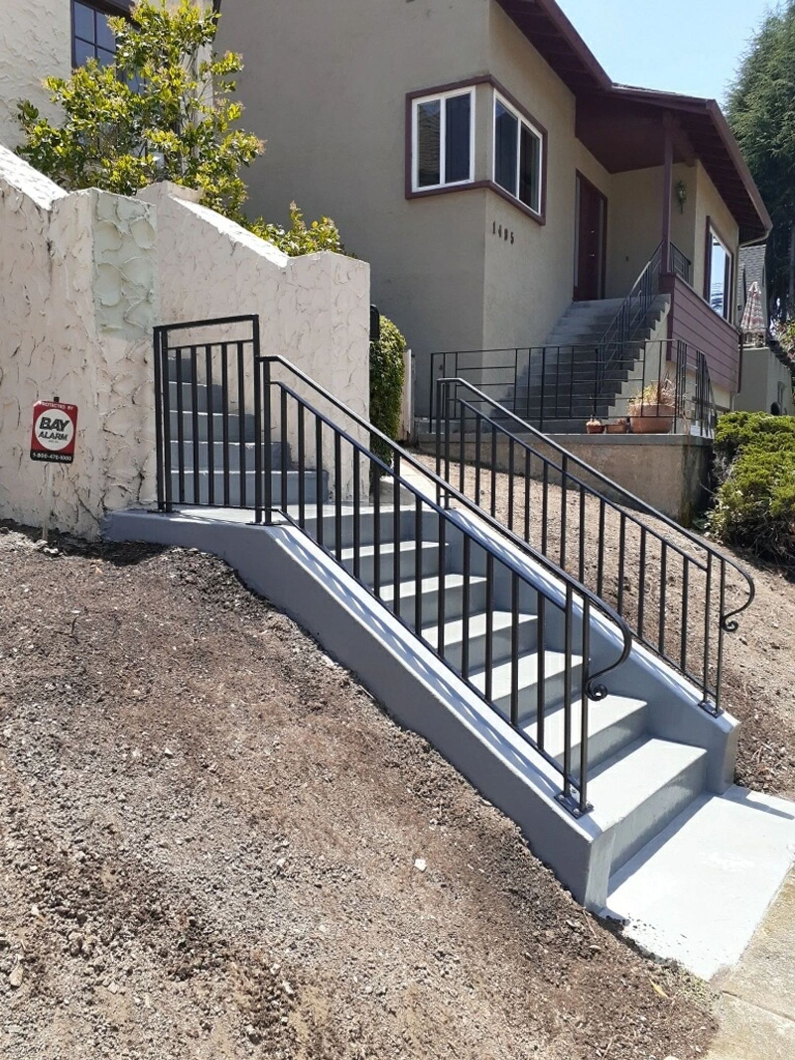 A black wrought-iron handrail on a curved exterior staircase, an ATR Welding installation