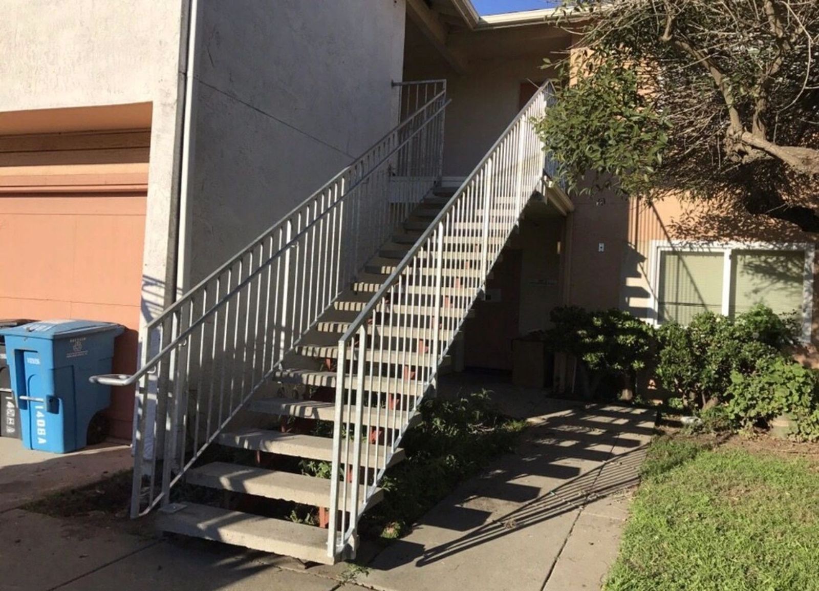 A white exterior stair railing beside concrete steps, an ATR Welding installation