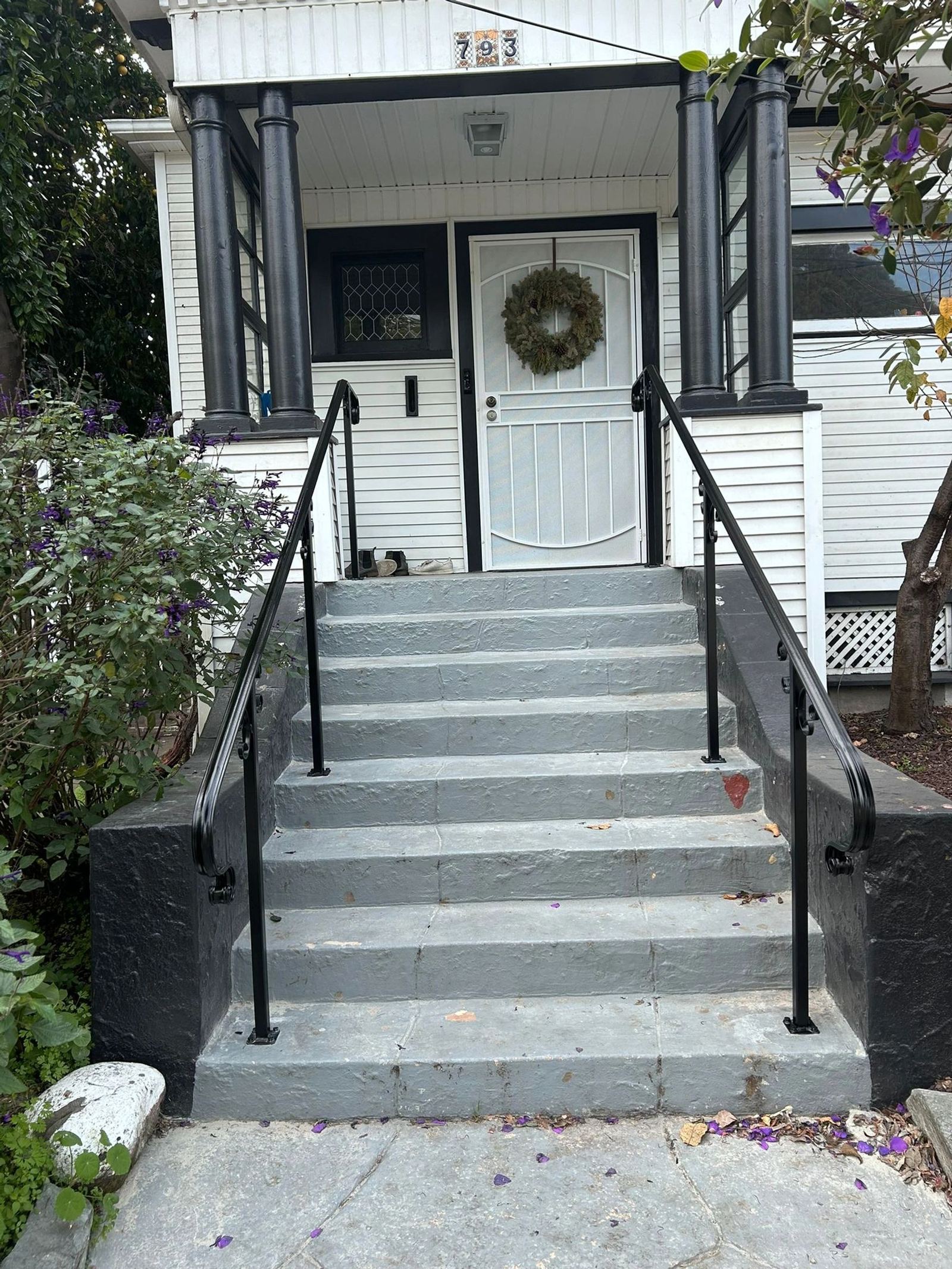 A black iron handrail on a front porch staircase, an ATR Welding installation