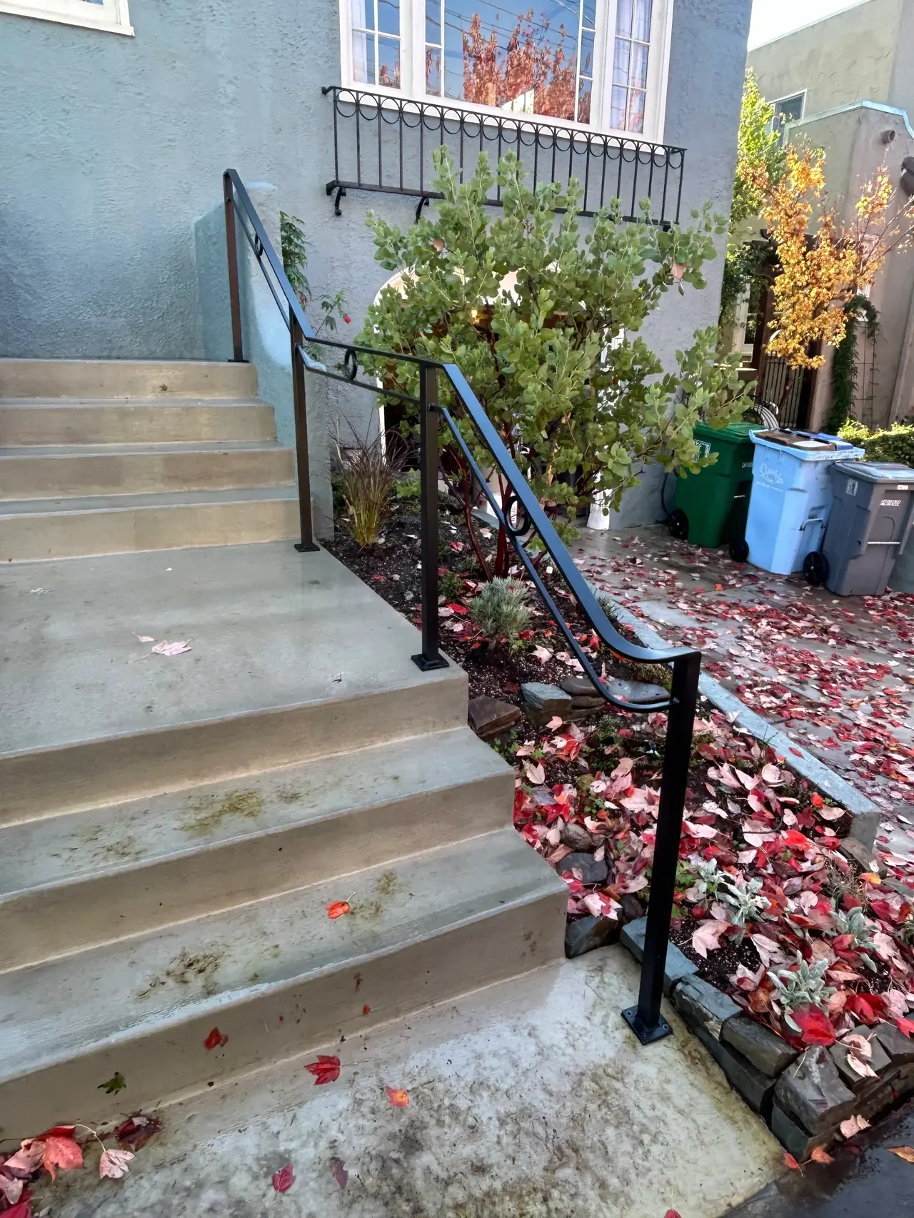 A curled-return exterior grab handrail beside concrete steps